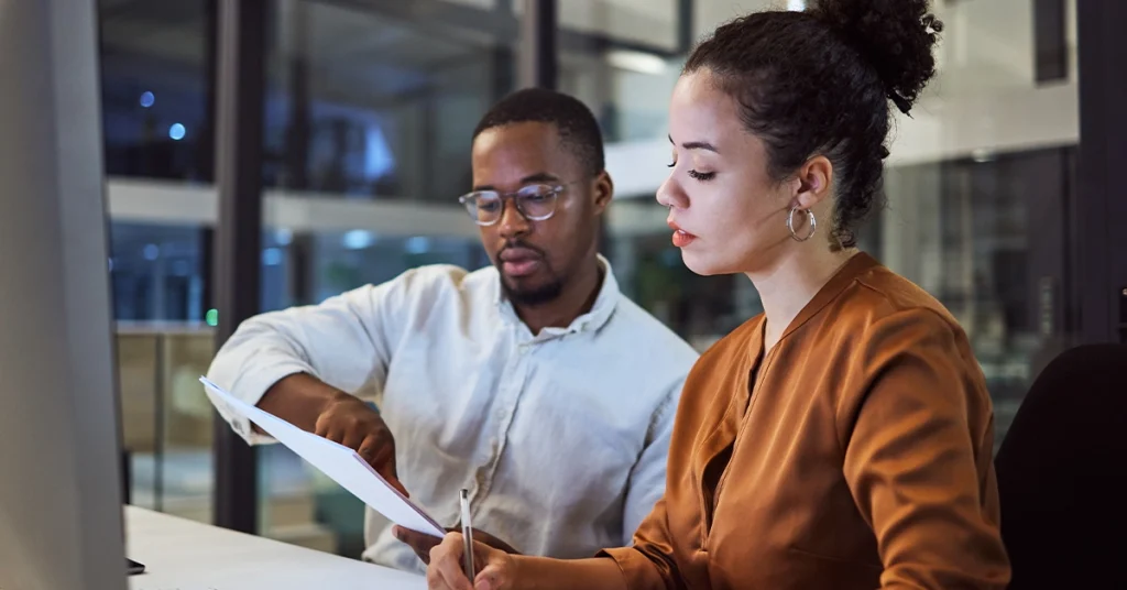 Two accounting professionals reviewing documents together in a office, representing starting salaries rising for accountants and finance professionals.