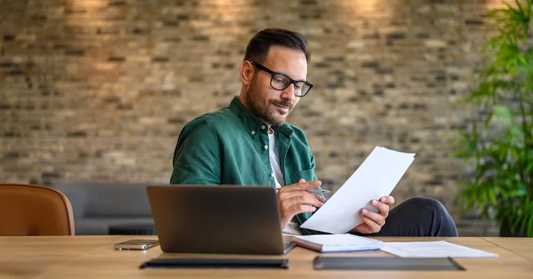 Focused accountant working at a desk with laptop and paperwork, representing the busy season buzz often shared by accountants on Twitter