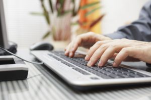man is typing on keyboard at home