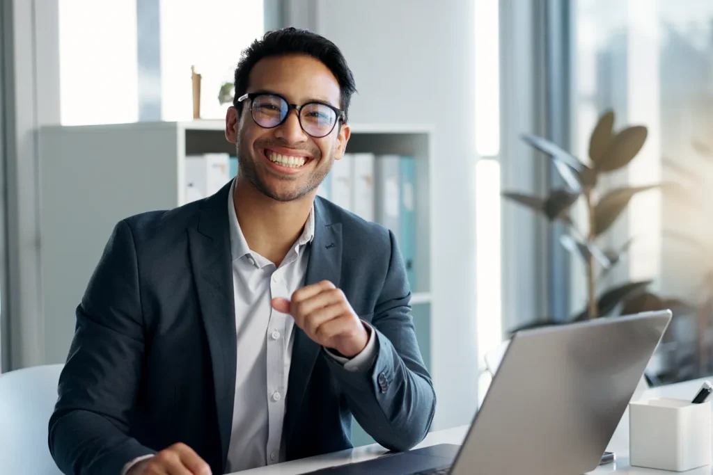 A CMA-certified professional smiling while working on his laptop