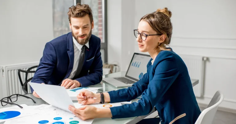 Two professionals in business attire reviewing financial charts and planning strategy, representing the best order to take CPA exams for optimal success.