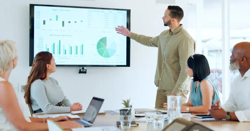 Young professionals sitting at conference table on laptops collaborating with each other