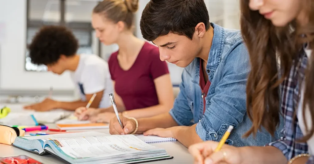 CPA students studying together in a classroom setting using textbooks and notebooks, focused on exam preparation with the Best CPA Study Materials.