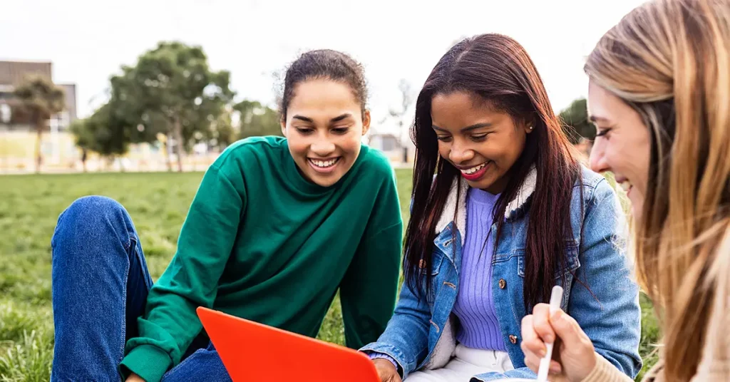 Three students are preparing together to pass the CPA exam on their first attempt, studying with a laptop and taking notes.