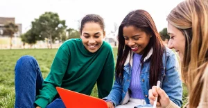 Three students are preparing together to pass the CPA exam on their first attempt, studying with a laptop and taking notes.