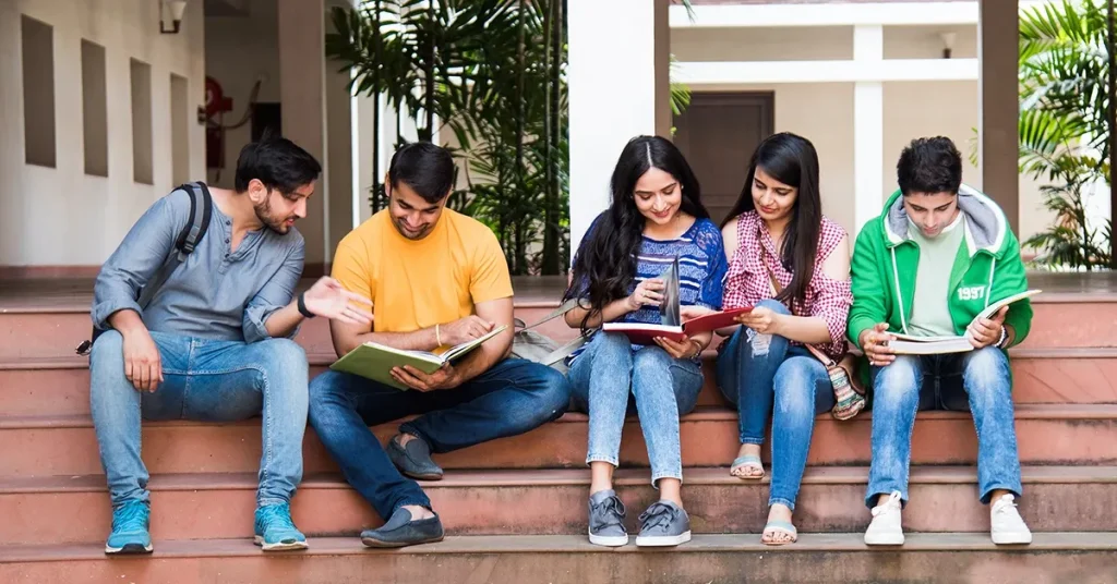 Group of diverse students sitting on campus steps reading CPA books and study guides