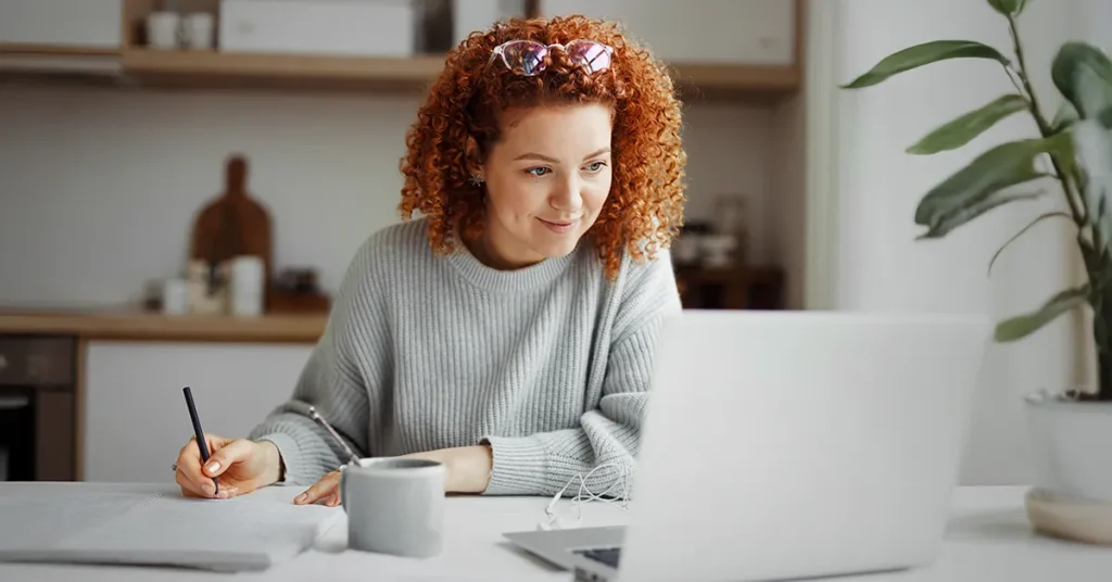 CMA candidate sitting at a desk with coffee, notebook and laptop studying UWorld CMA course materials