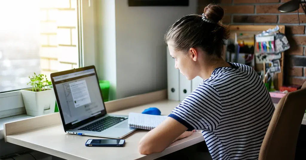CPA student using video lectures and notes for focused exam preparation at a study desk