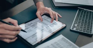 A tax accountant sits at their desk and tracks expenses on their tablet.